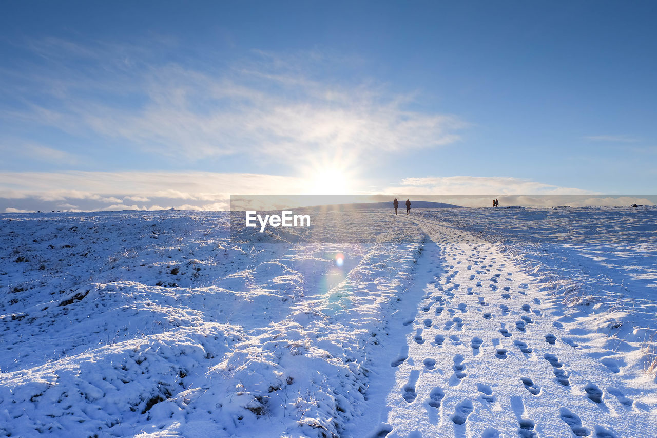 Distant people walking on snow covered field