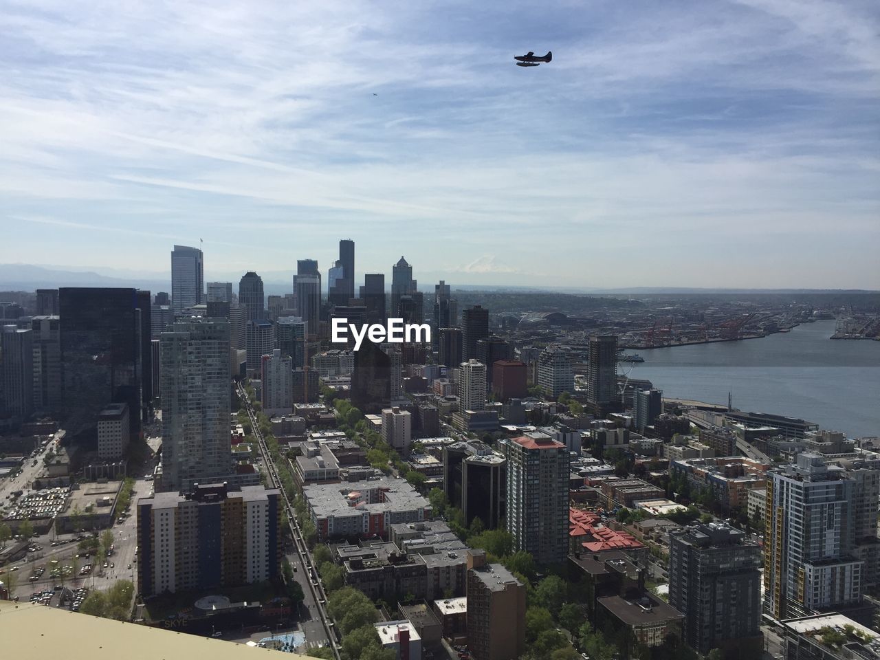 High angle view of buildings in city against sky with plane