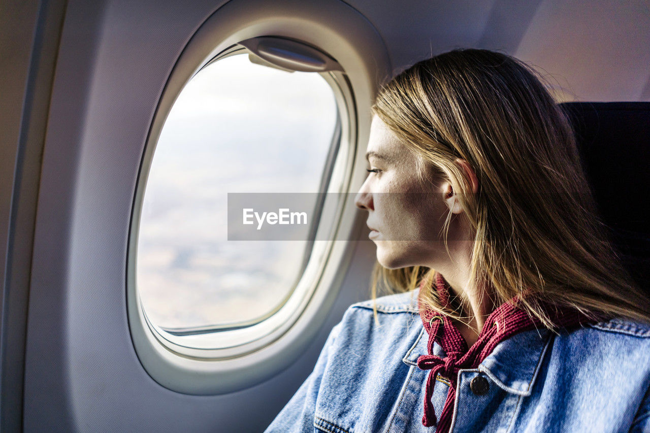 Woman looking out of window sitting in airplane
