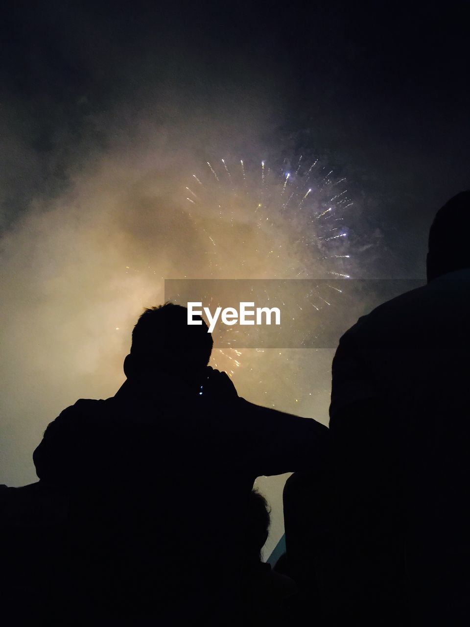 Low angle view of silhouette people against firework display at night