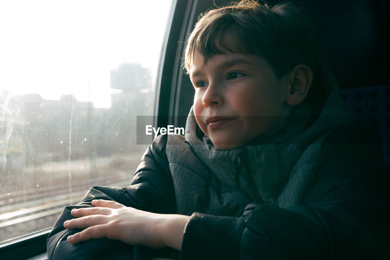 Boy looking through window while traveling in train