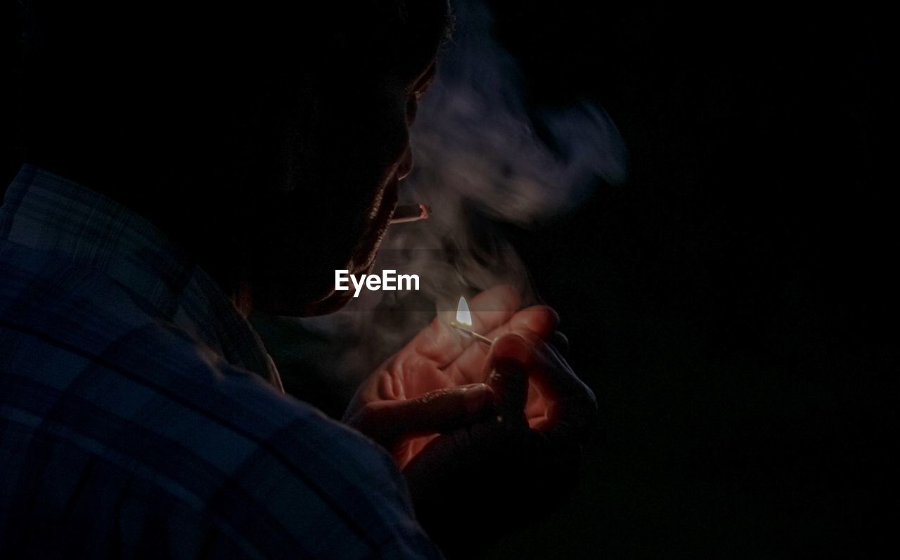 Man smoking cigarette against black background