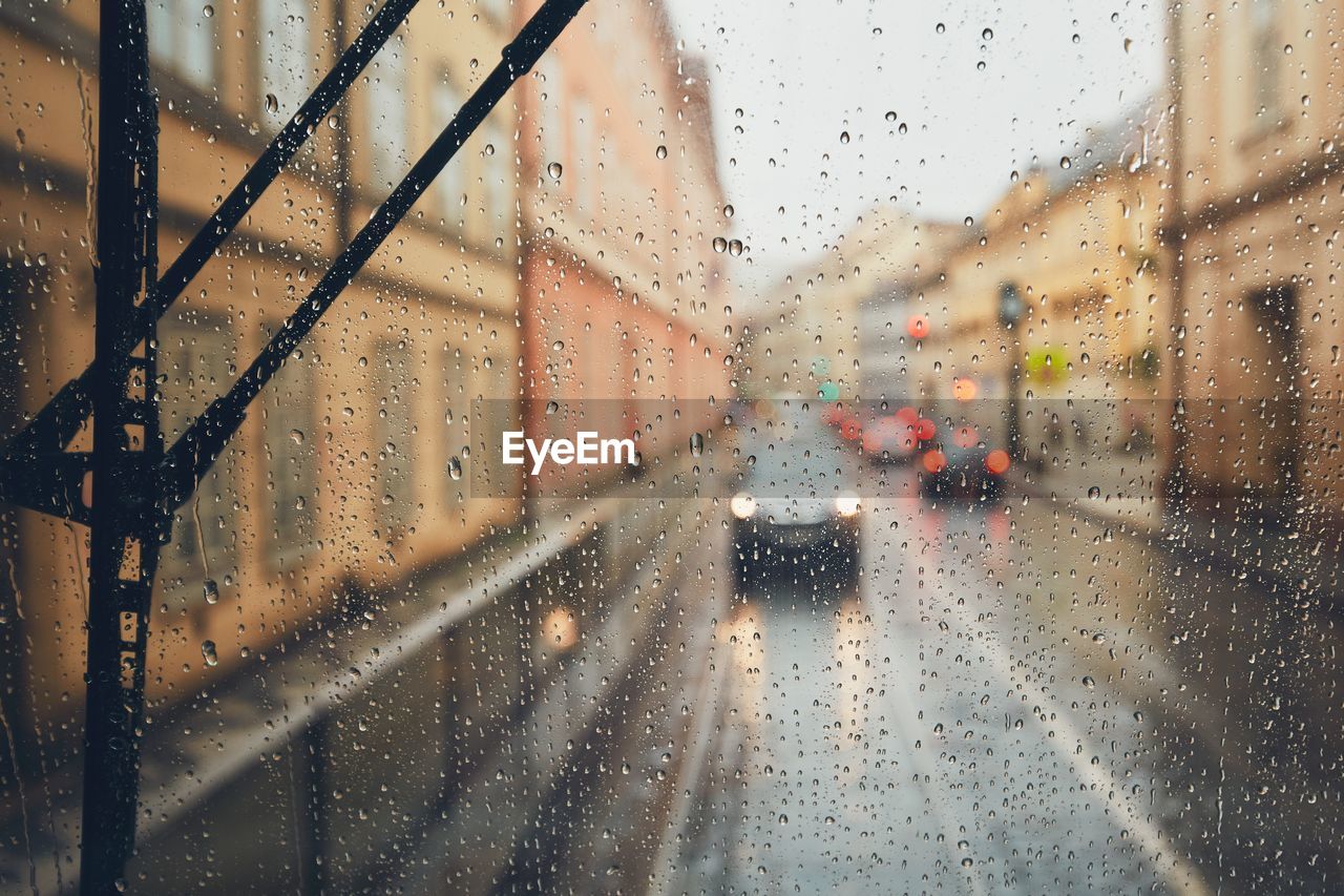 Car on street seen through wet glass window