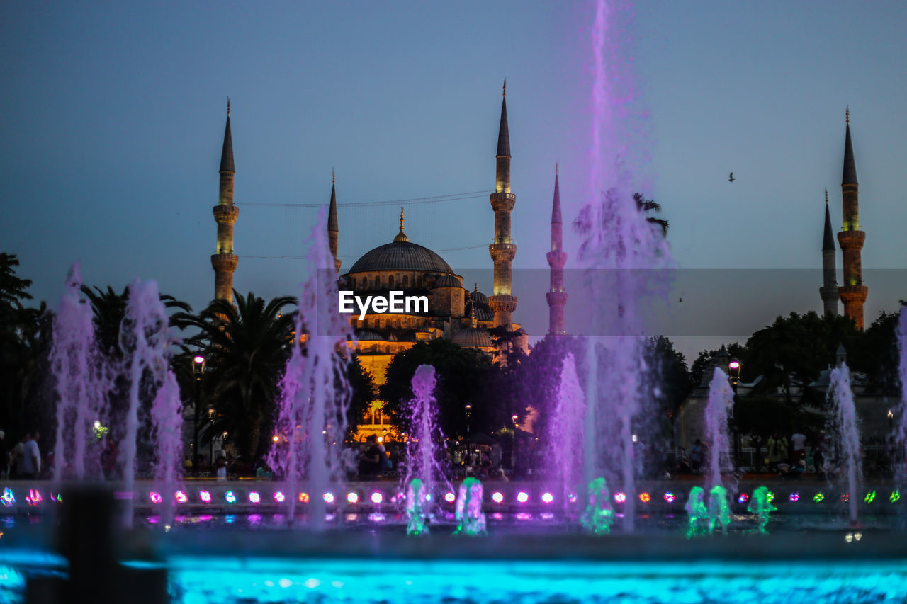 Mosque with purple fountain water as a postcard in sunset with minarets and blue sky