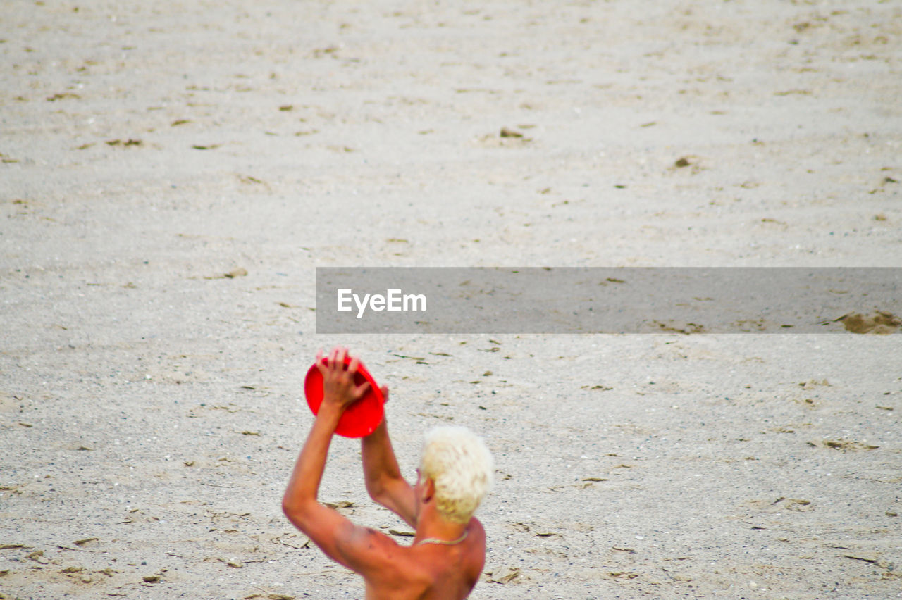 High angle view of man playing with plastic disc at beach