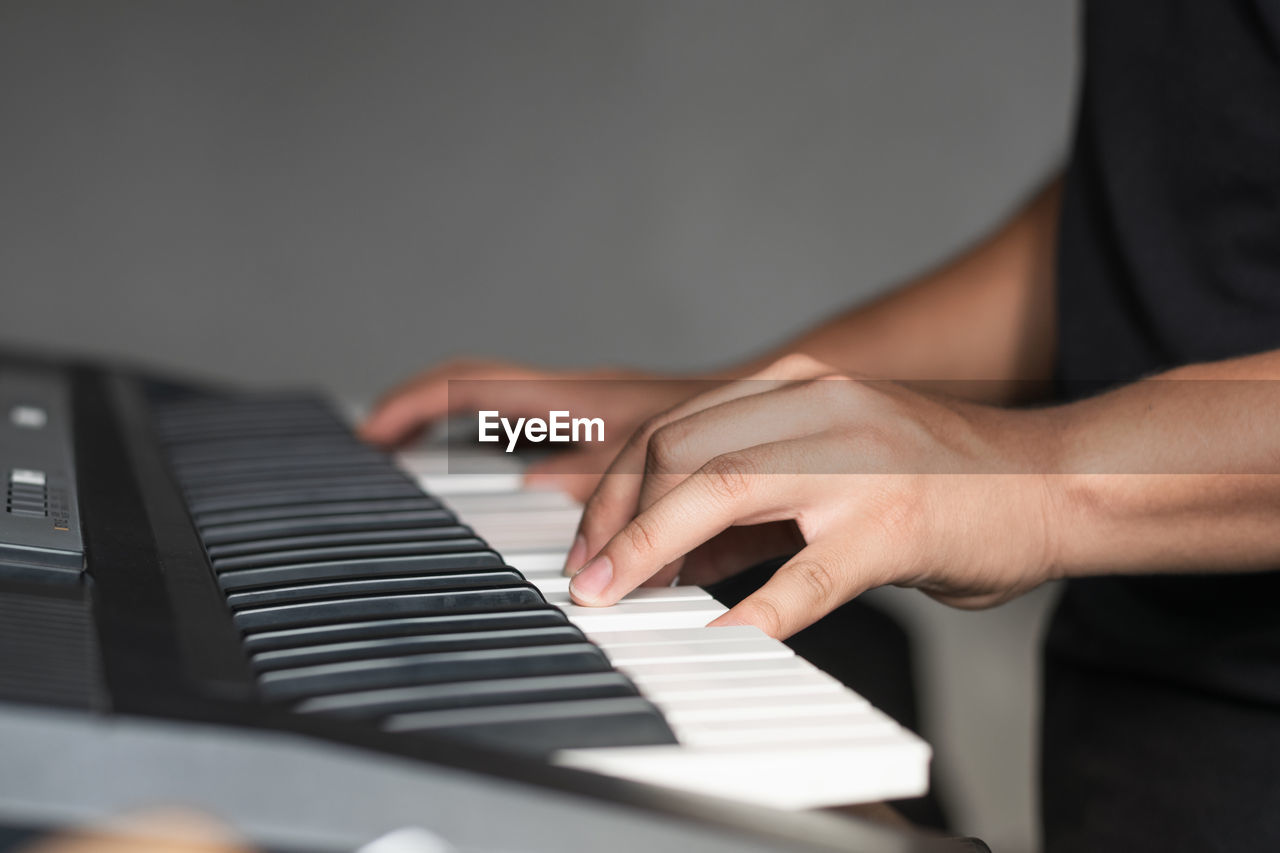cropped hand of man playing piano