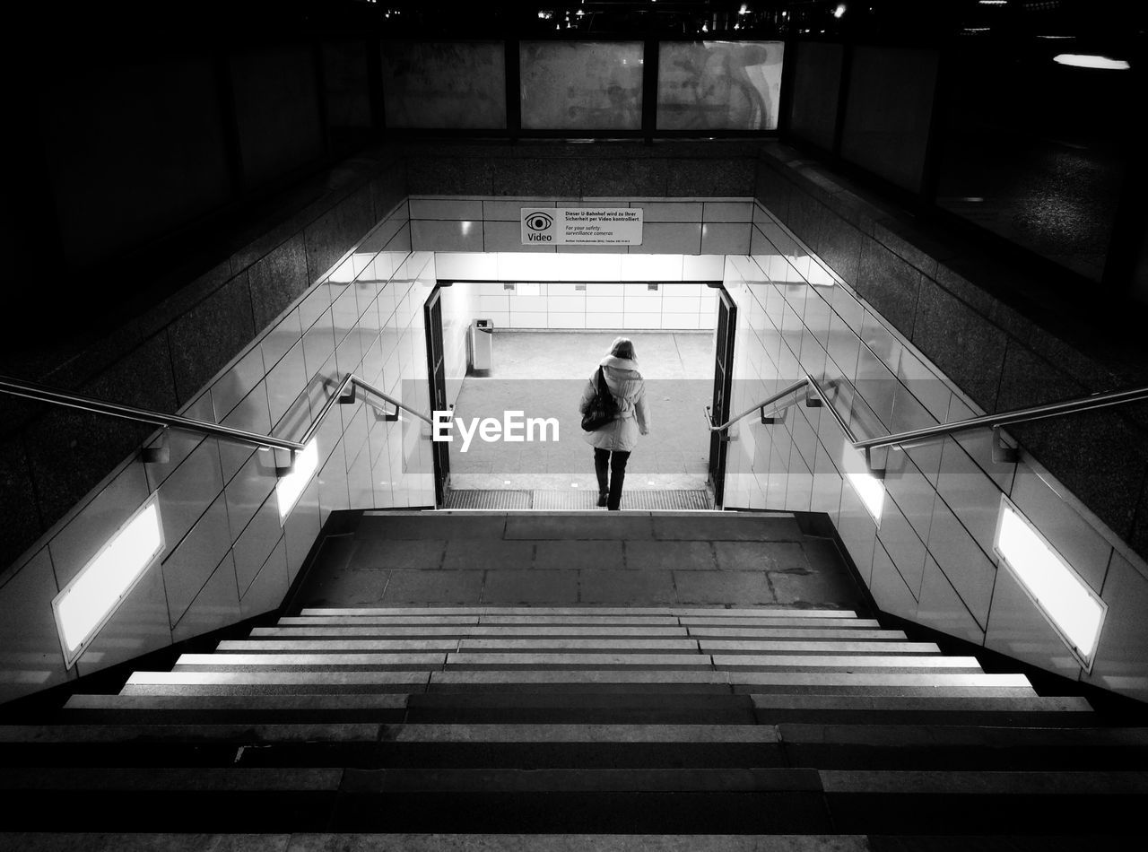 Rear view of woman moving down on steps at night