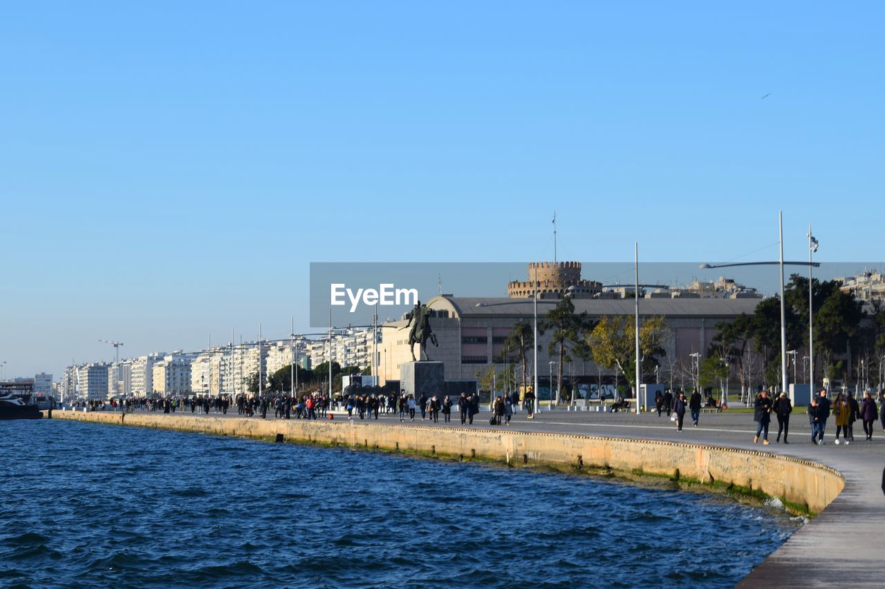 View of buildings by sea against clear blue sky