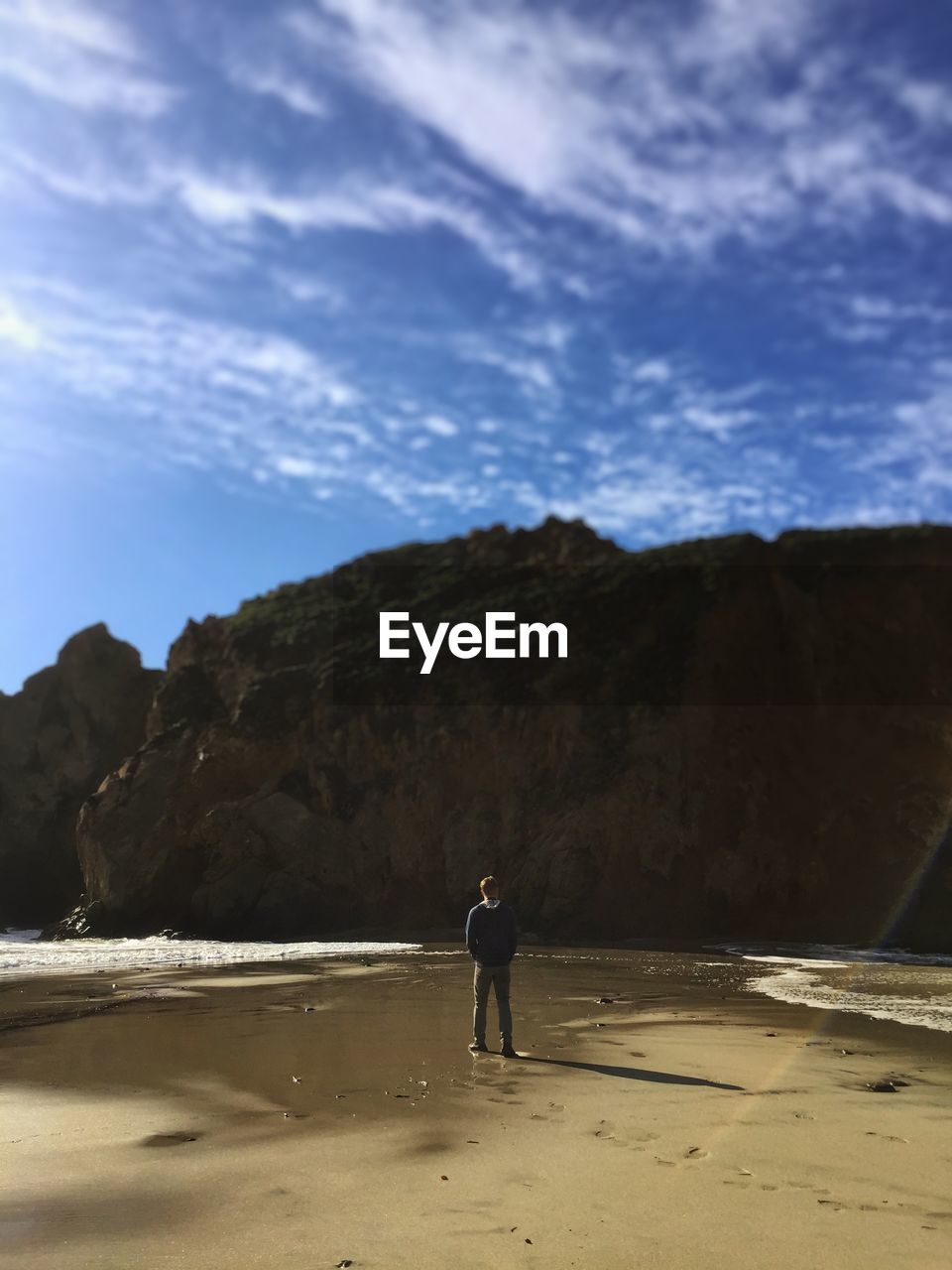 Man standing on lakeshore against mountain