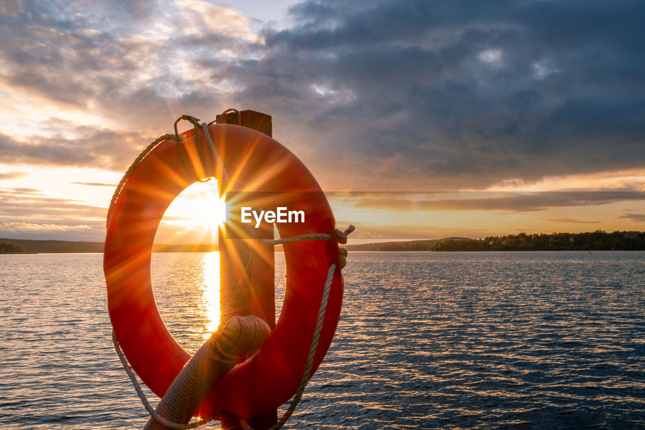 Lifebelt hanging on wooden post at lake wannsee during sunset