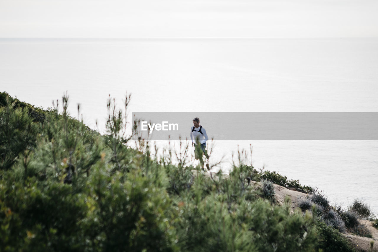 Man running up on mountain by sea