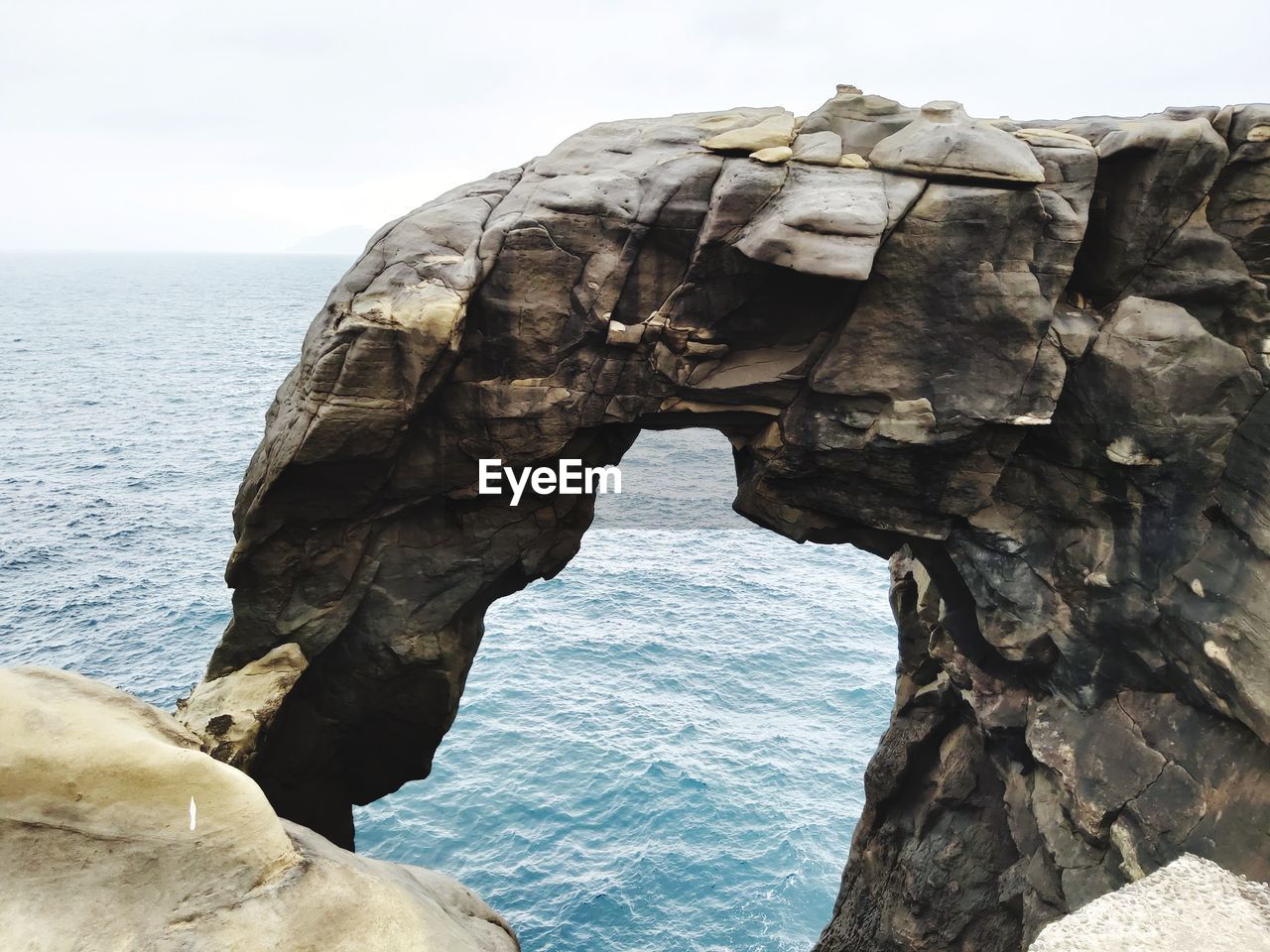 Rock formation in sea against clear sky