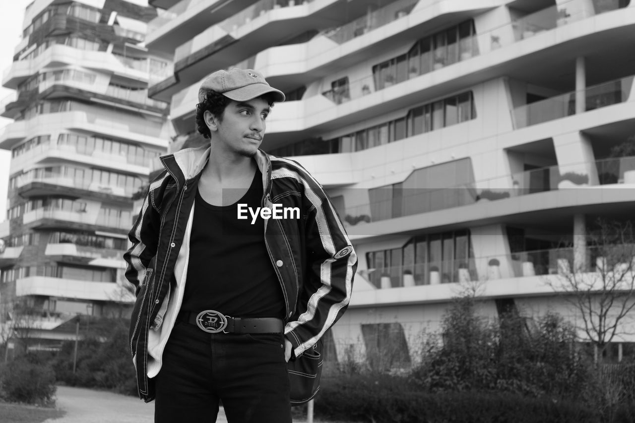 Portrait of young man standing against buildings