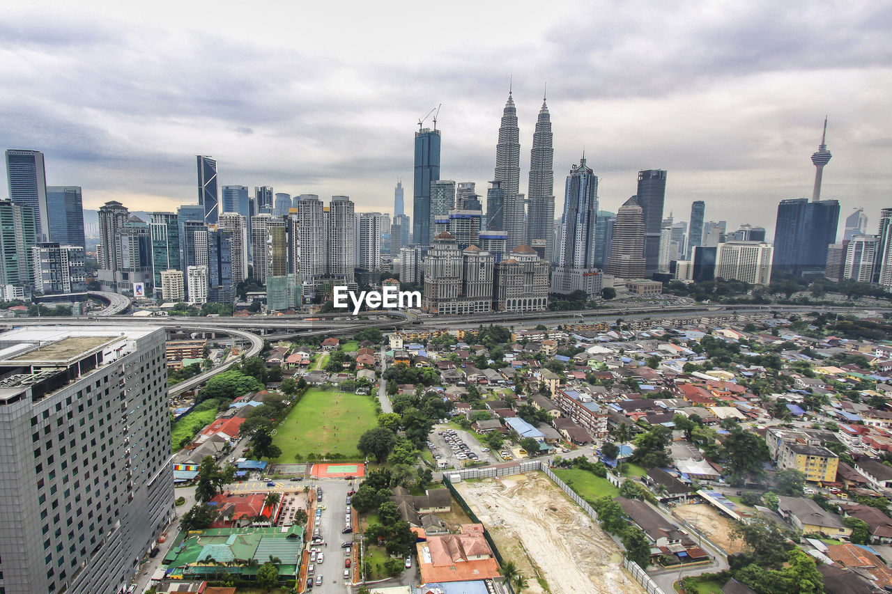 High angle view of city buildings against cloudy sky