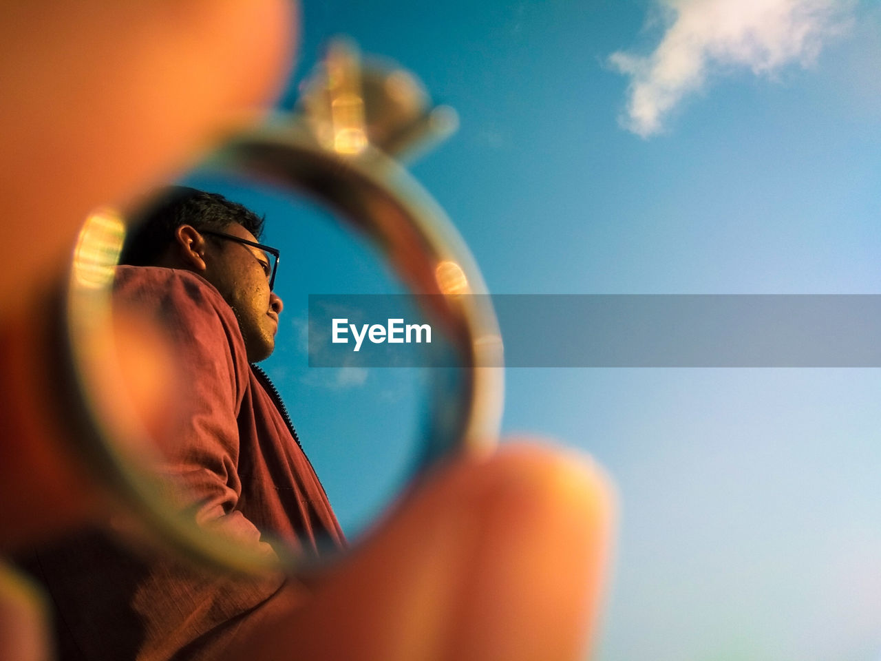 Low angle view of man seen through ring against sky