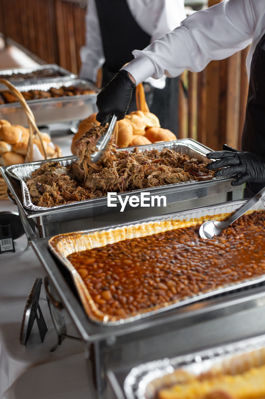 Midsection of people serving food in kitchen