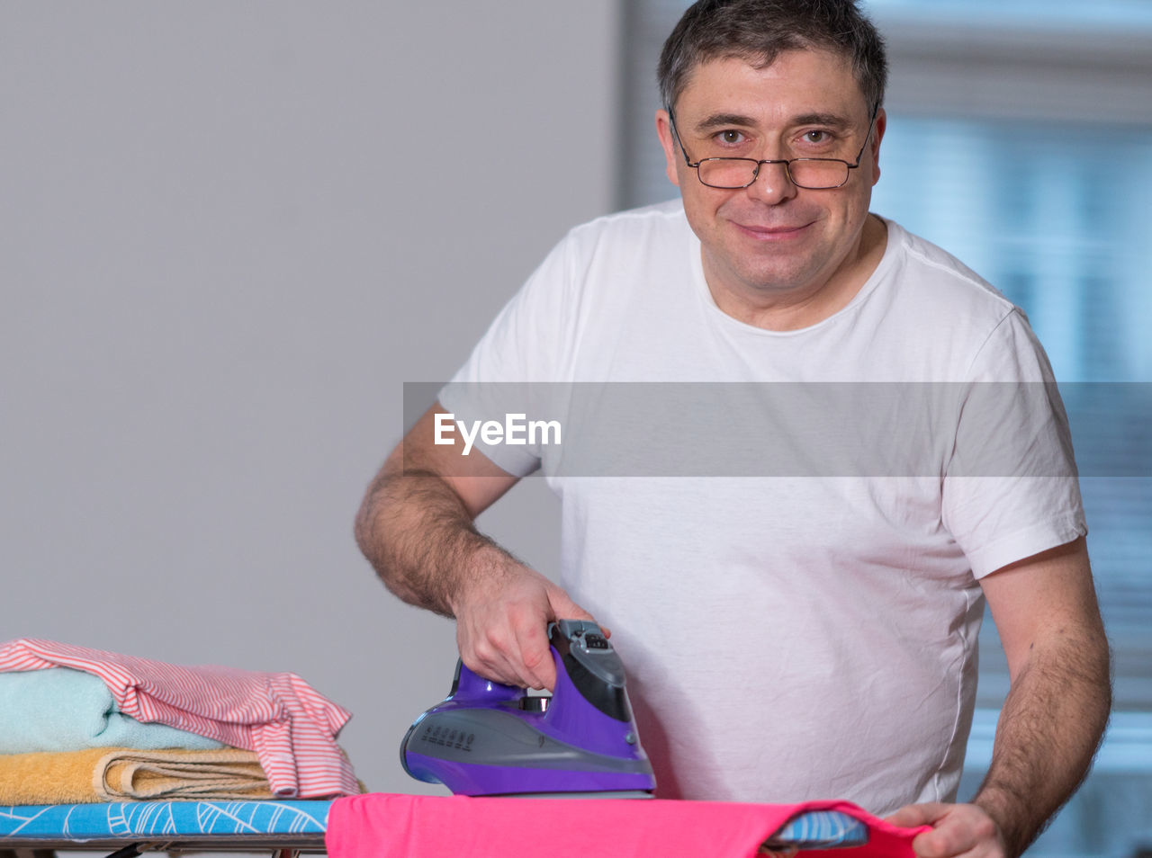 Portrait of man ironing cloth at home