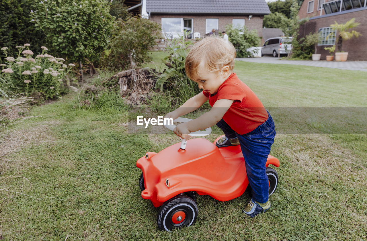 Full length of cute girl playing with toy car on field