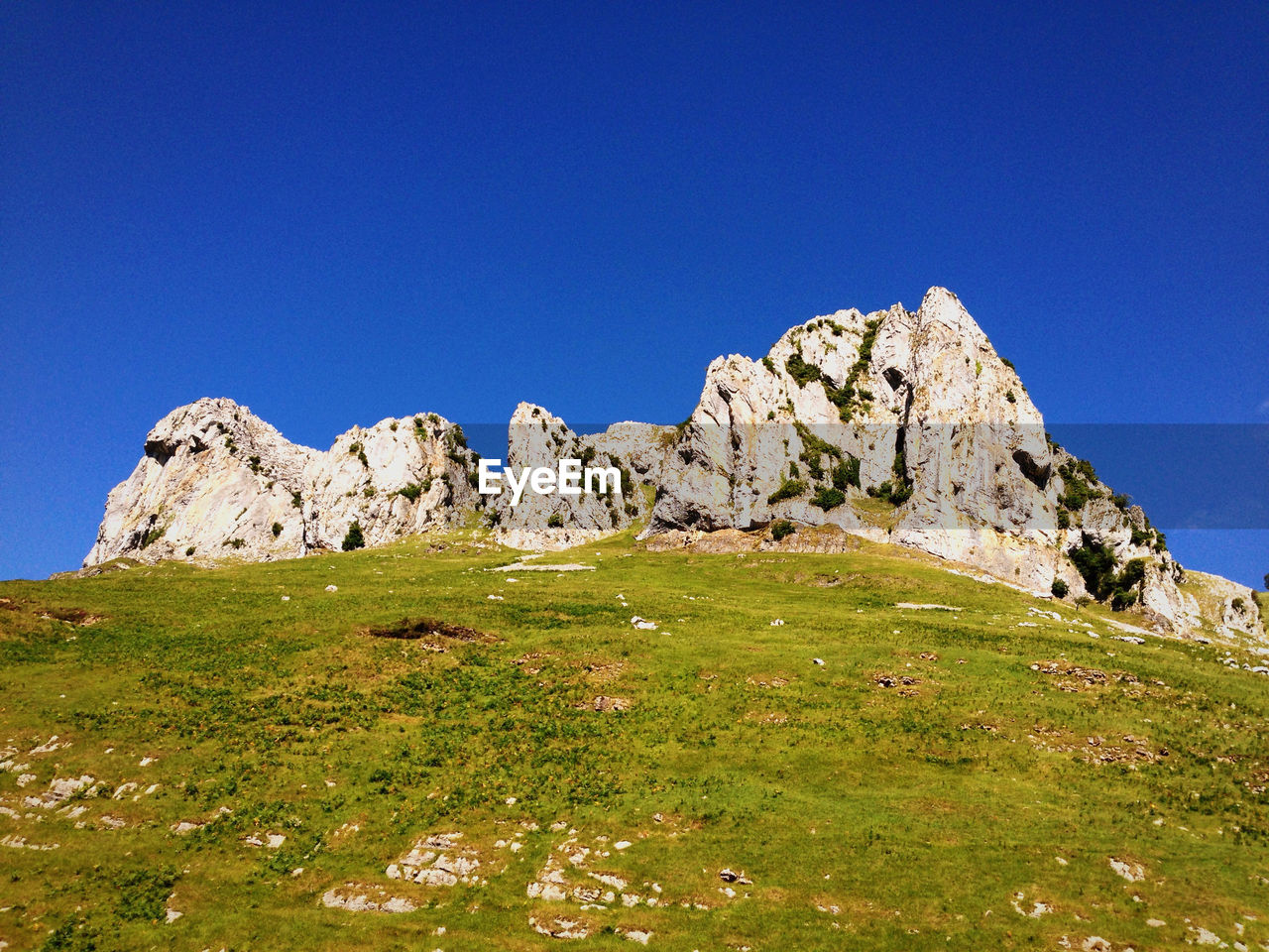 Low angle view of rocks against clear blue sky