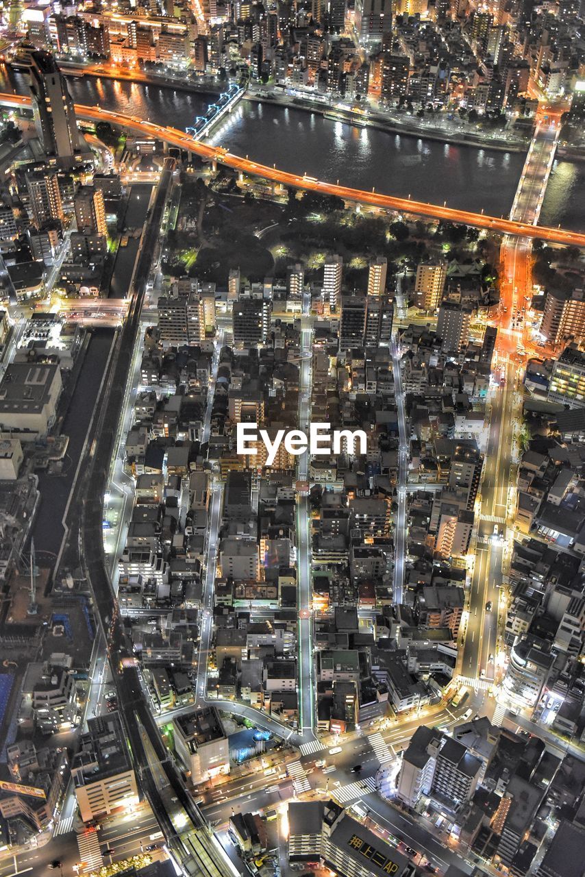 HIGH ANGLE VIEW OF ILLUMINATED CITY BUILDINGS AT NIGHT