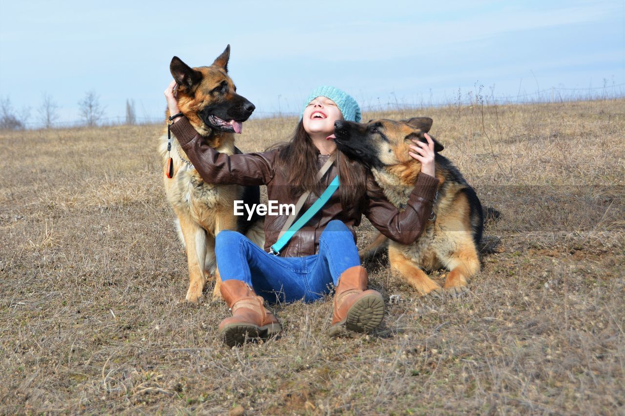 Girl sitting with dogs on field