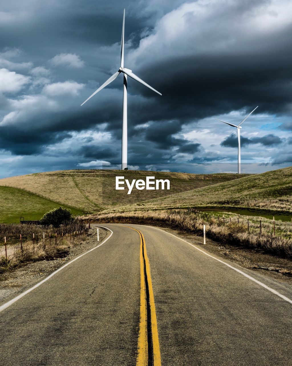 Windmill on road against sky