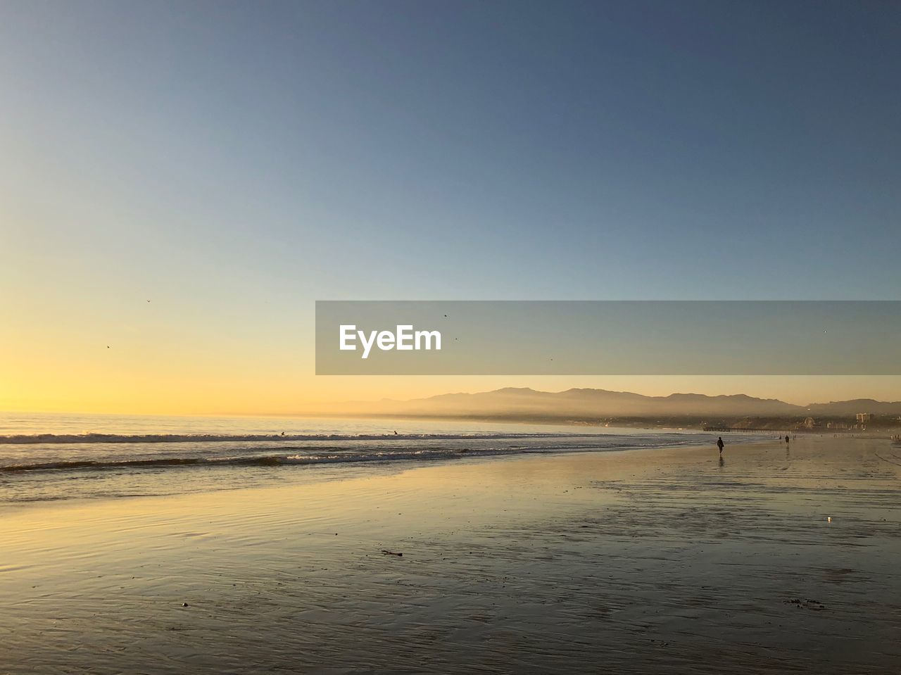 Scenic view of beach against clear sky during sunset