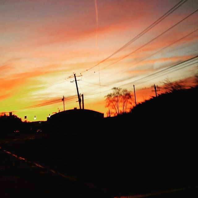 SILHOUETTE OF POWER LINES AGAINST SUNSET SKY