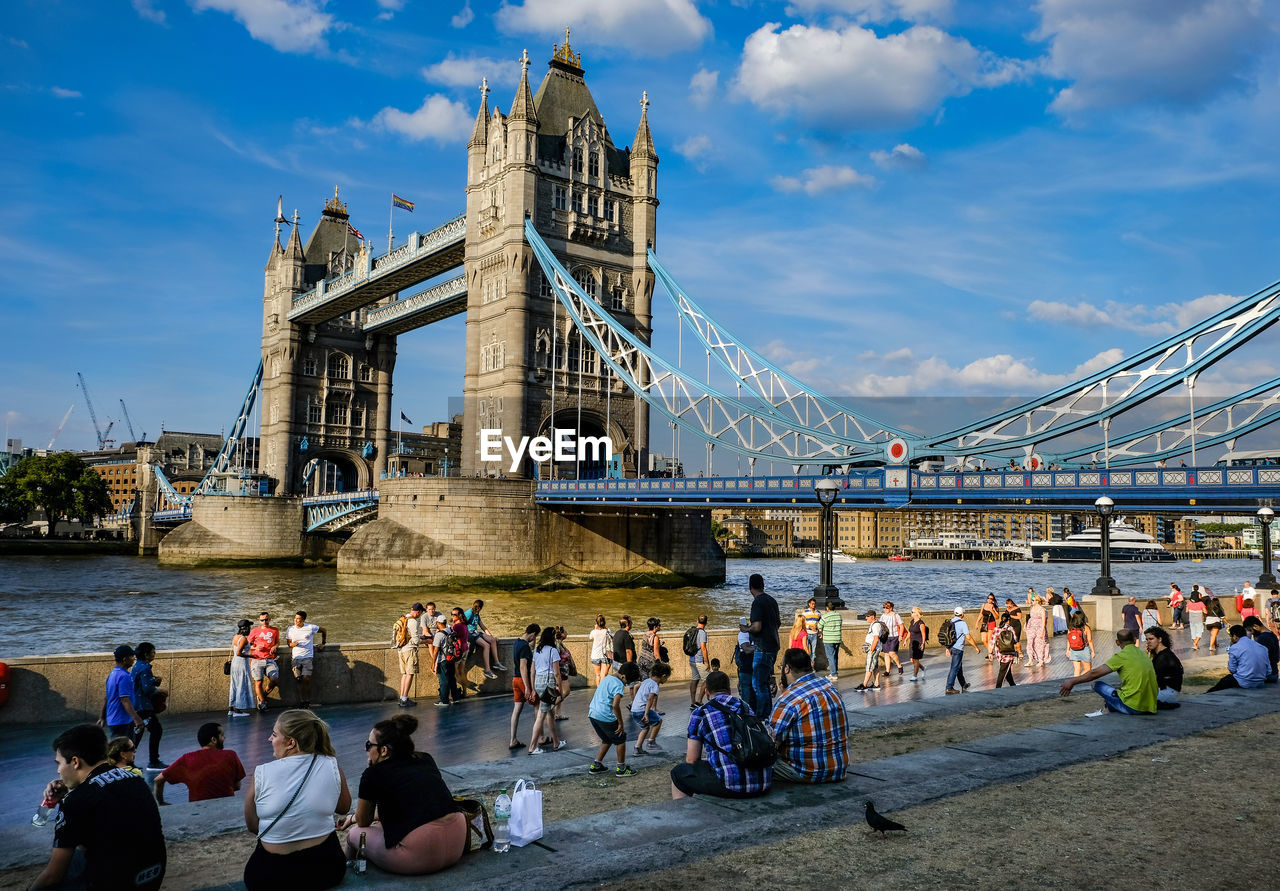 People at tower bridge against cloudy sky