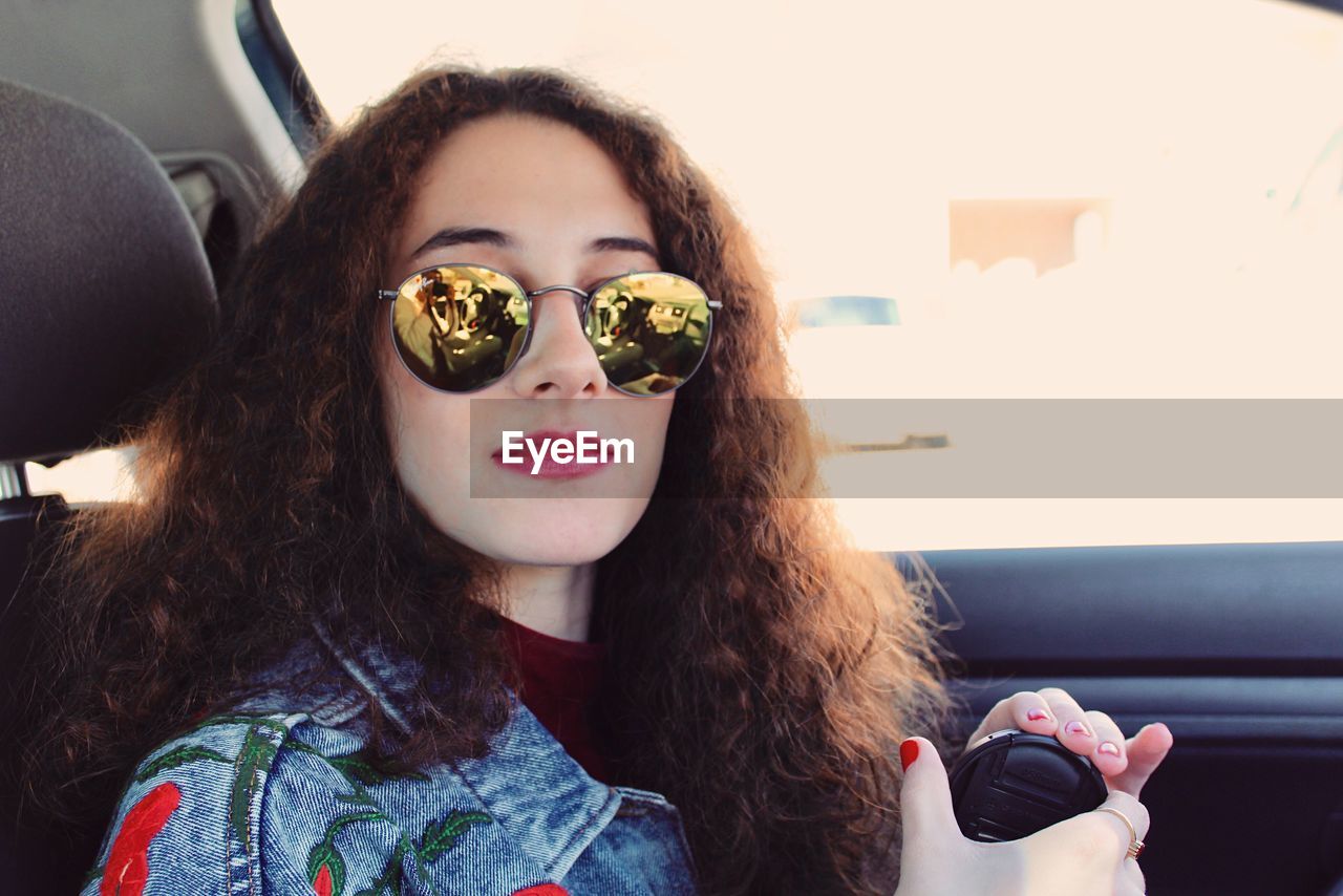 Close-up portrait of young woman wearing sunglasses in car