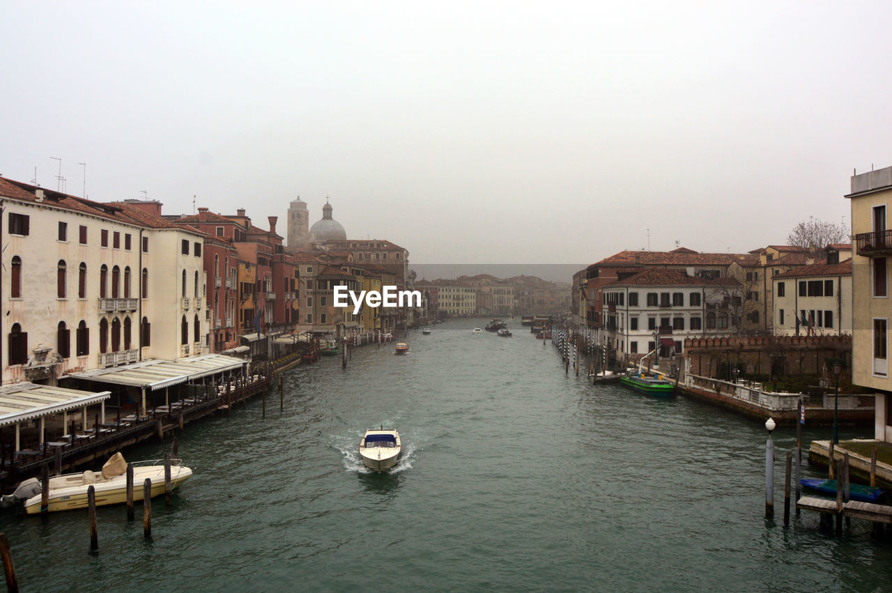 Canal in city against clear sky