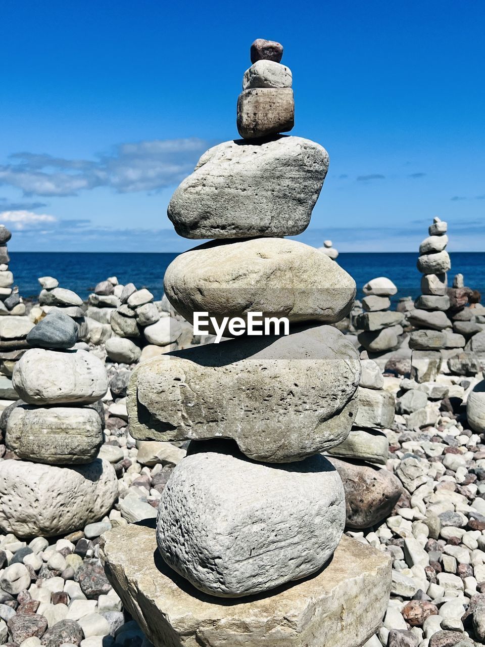 rock, stone, balance, sea, sky, pebble, nature, water, shore, zen-like, coast, beach, land, tranquility, no people, tranquil scene, day, blue, beauty in nature, scenics - nature, ocean, large group of objects, sand, boulder, outdoors, cloud, sunlight, statue, sunny
