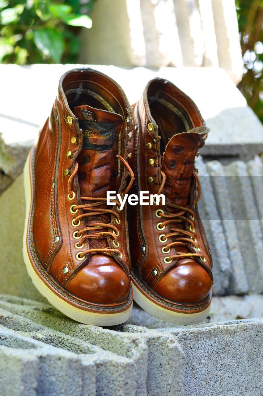 CLOSE-UP OF SHOES ON RETAINING WALL OUTDOORS