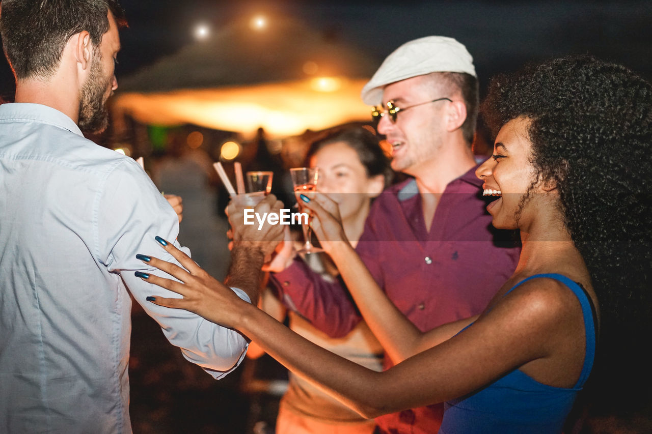 Friends toasting drink in party at night