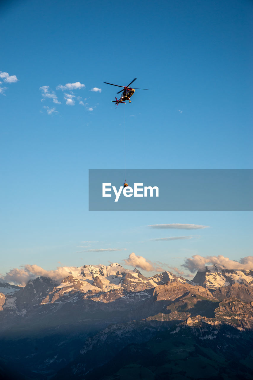 Helicopter flying over landscape against sky