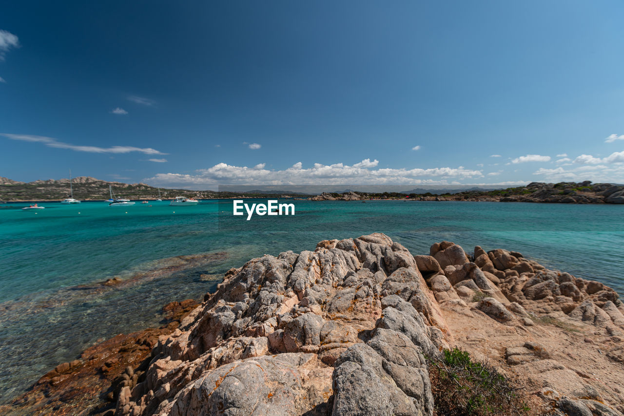 SCENIC VIEW OF ROCKY BEACH AGAINST BLUE SKY