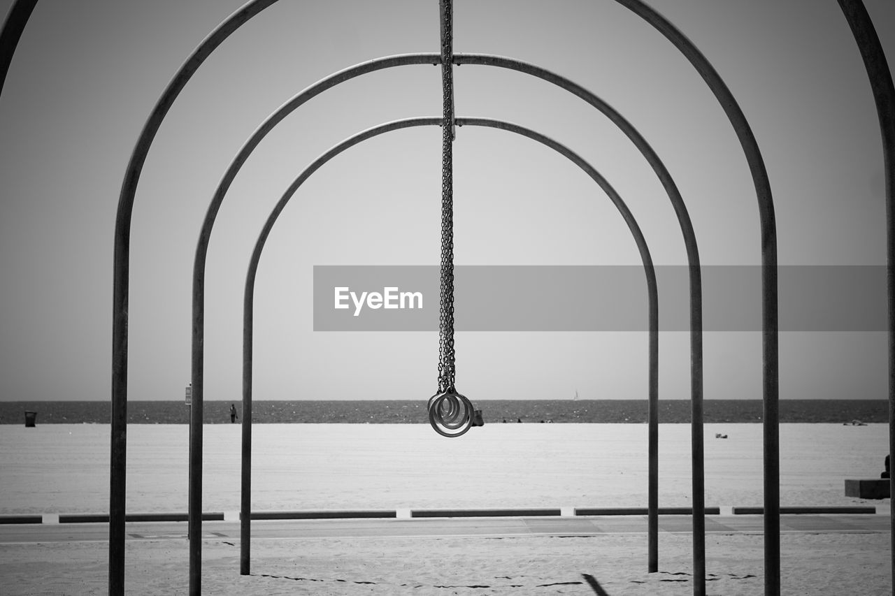 Metallic rings on beach against clear sky