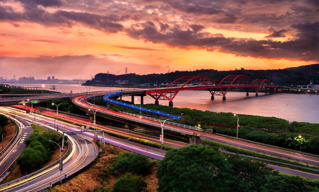 HIGH ANGLE VIEW OF BRIDGE OVER ROAD AGAINST SKY DURING SUNSET