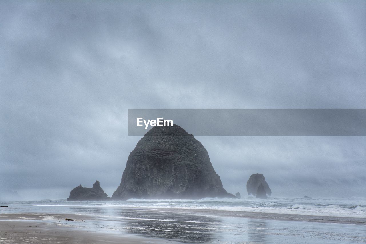 Rock formation on beach against sky