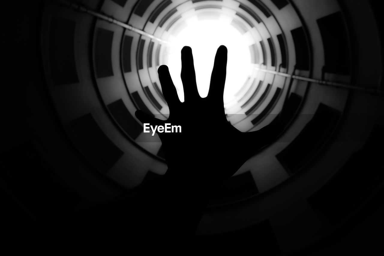 Directly below shot of cropped silhouette hand against skylight