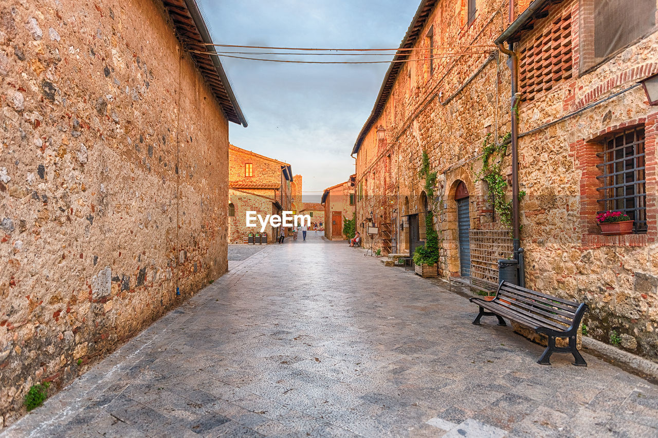 EMPTY ALLEY AMIDST BUILDINGS AGAINST SKY