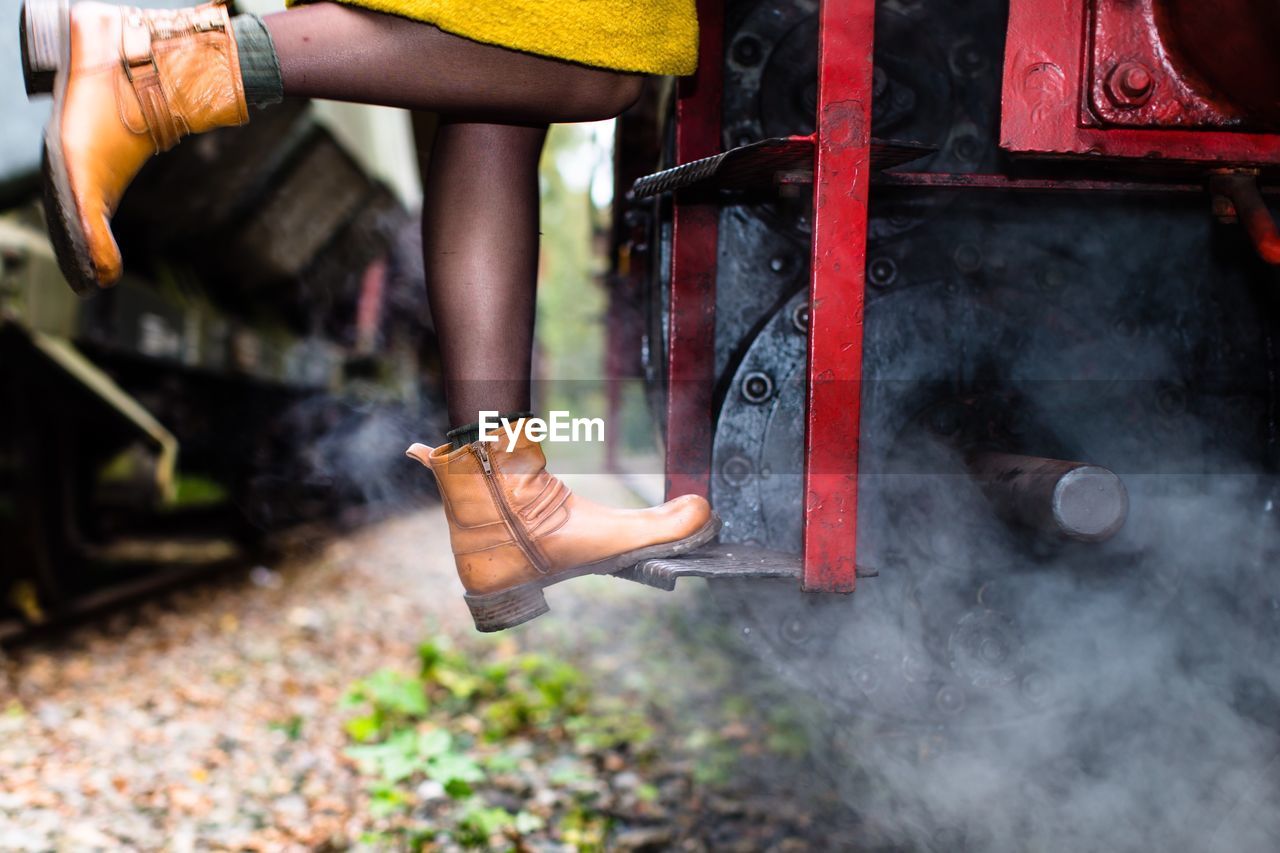 Low section of woman standing on stream train