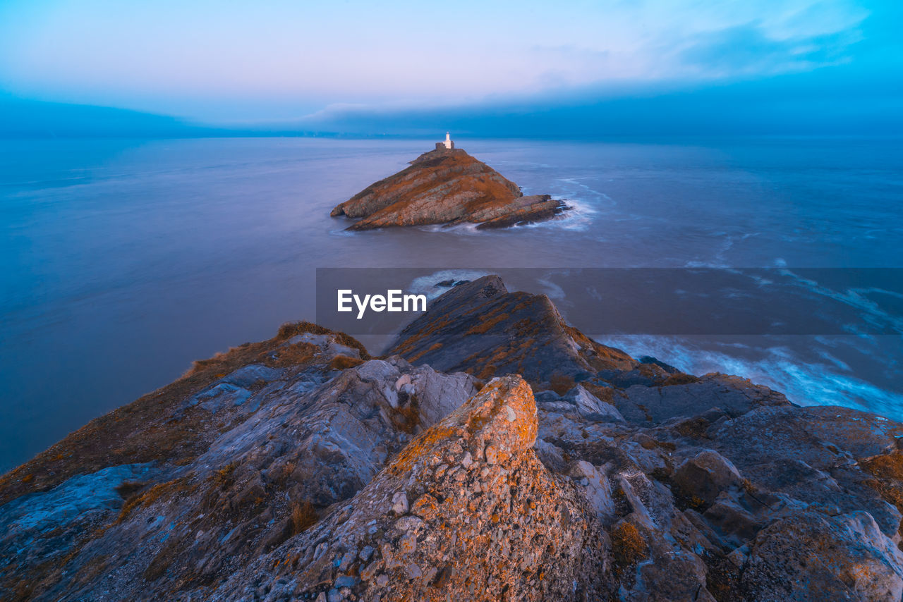 Rock formation in sea against sky