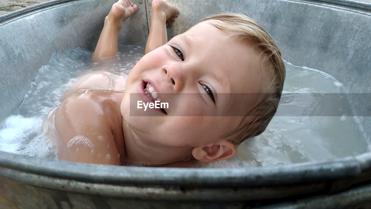 Smiling boy in the bathtub with foam
