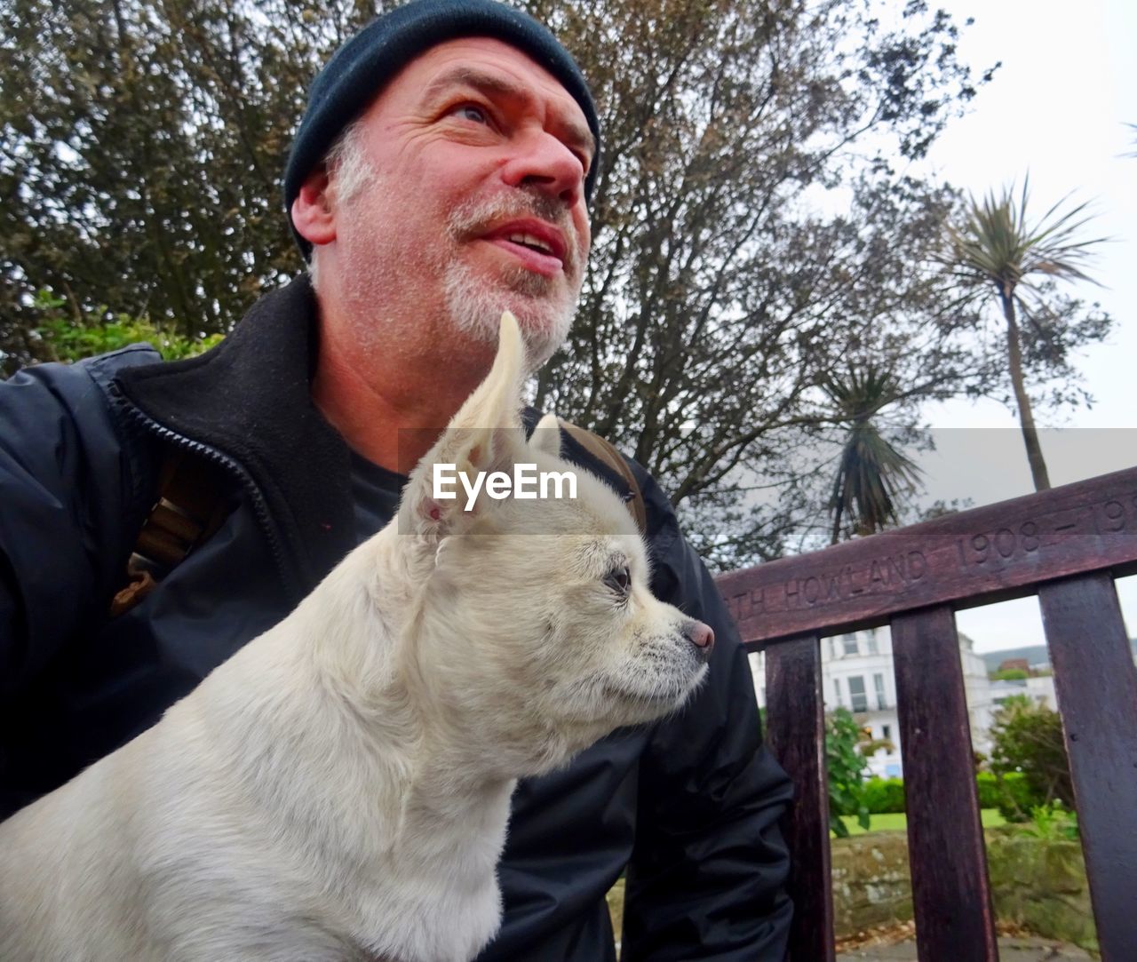 Man looking away with dog against tree