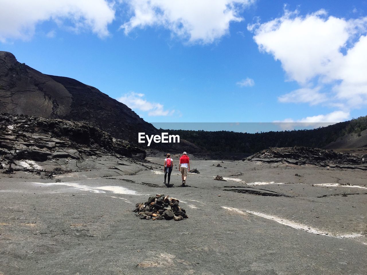 Rear view of hikers walking at kilauea iki crater against sky