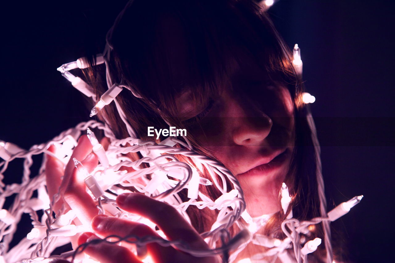 Teenage girl with illuminated string light in darkroom