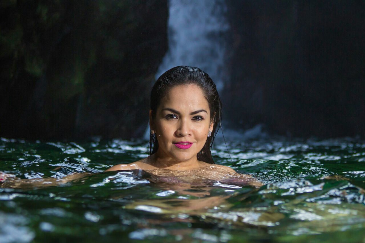 Portrait of beautiful woman swimming in lake at forest