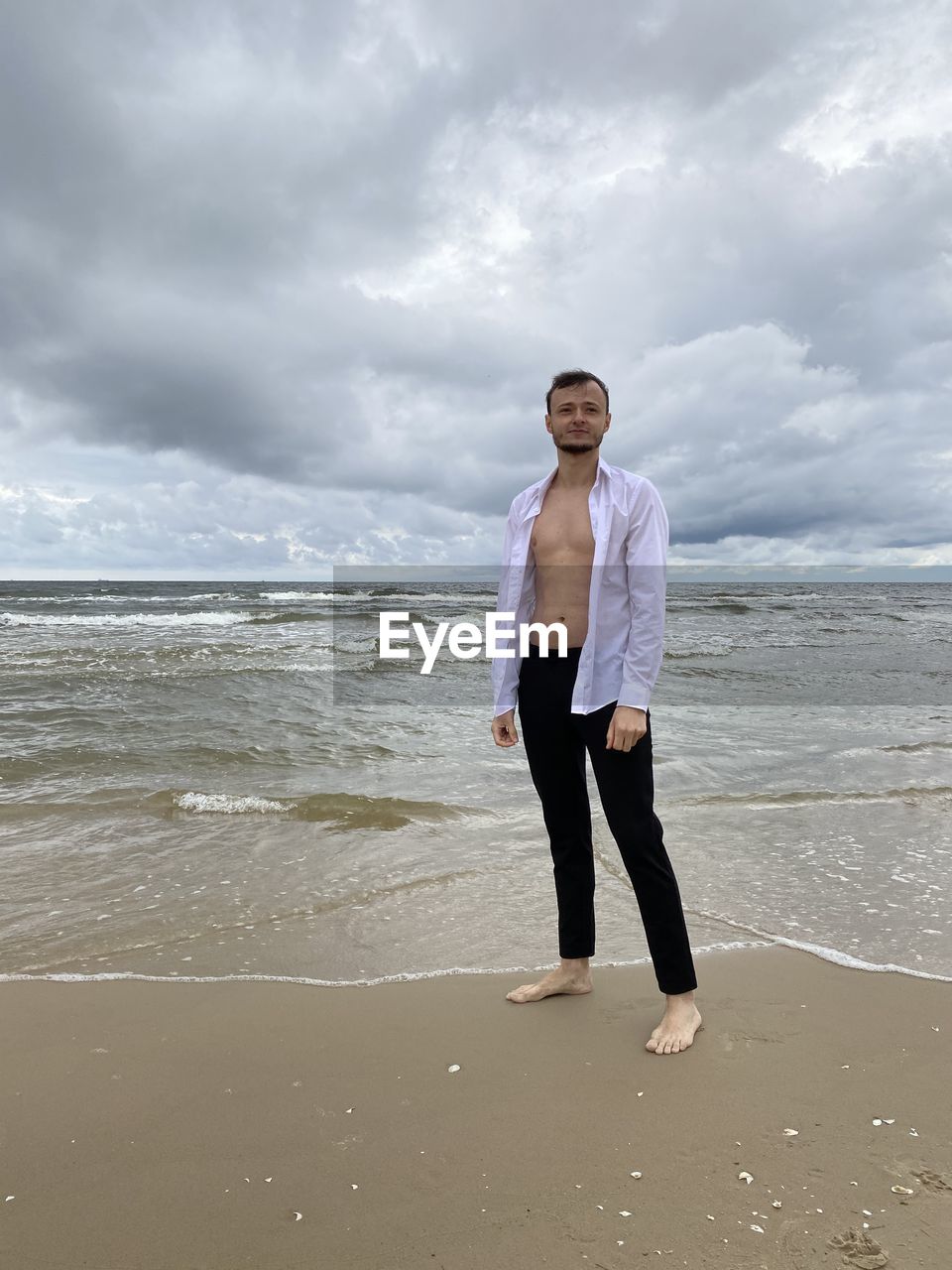 PORTRAIT OF MAN STANDING ON BEACH