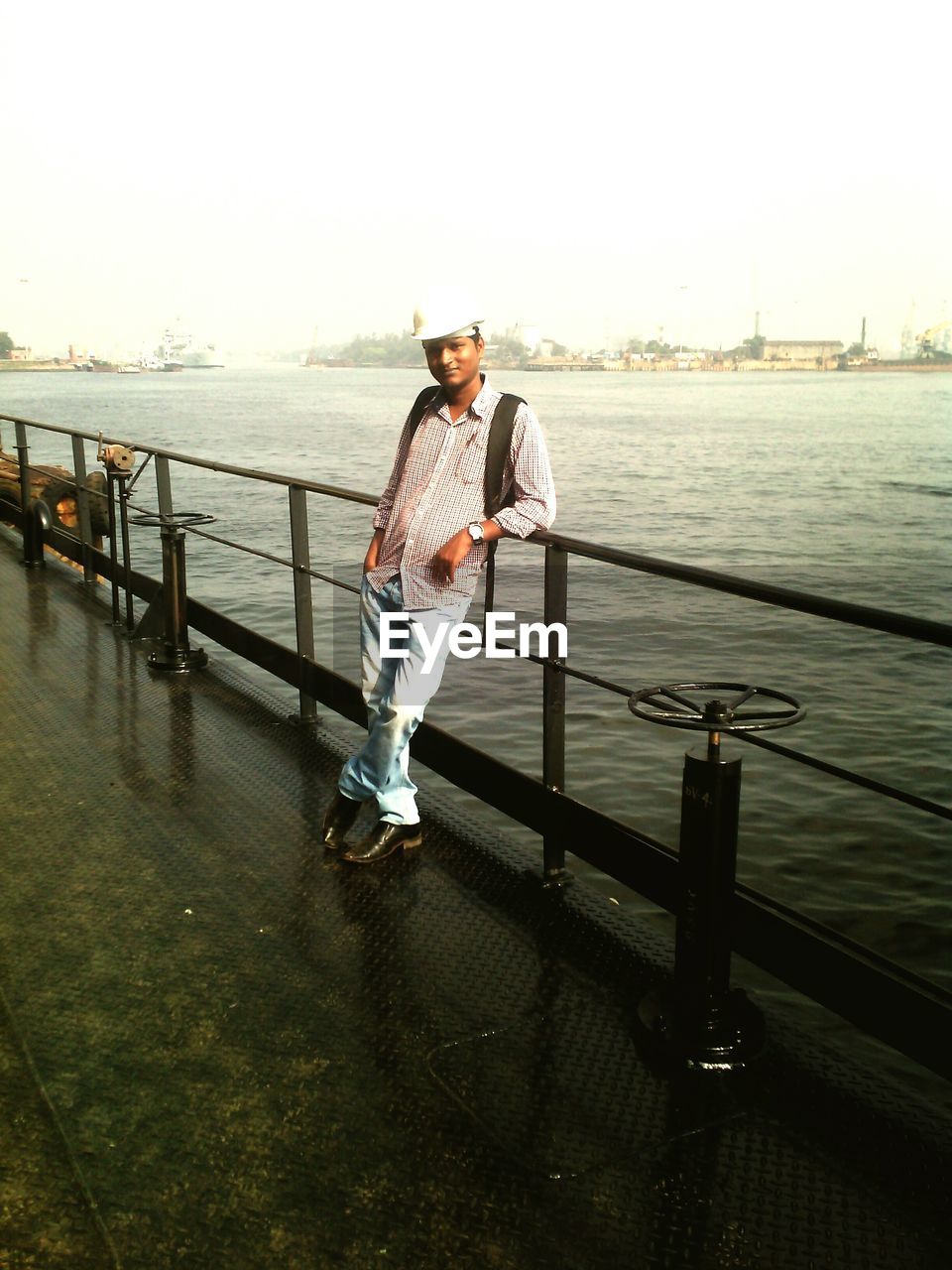 Full length of man standing by railing on boat in sea and sky